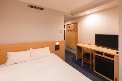 a hotel room with a bed and a desk with a television at Sotetsu Fresa Inn Tokyo-Akasaka in Tokyo