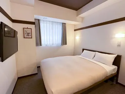 a bedroom with a large white bed with a window at The OneFive Tokyo Shibuya in Tokyo