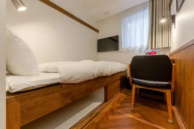 a bed and a chair in a small room at The OneFive Tokyo Shibuya in Tokyo