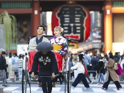 a man pushing a woman in a wheelchair down a street at Hotel Gracery Asakusa in Tokyo
