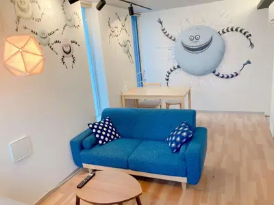 a living room with a blue couch and a wall with monsters at The Aoca Tokyo Sanno in Tokyo