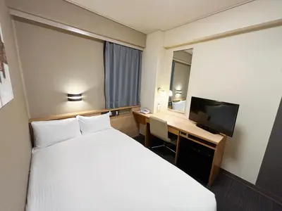 a hotel room with a bed and a desk with a television at Hotel Route-Inn Shinagawa-Oimachi in Tokyo