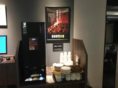 a counter with a drink dispenser with plates and dishes at Hotel Route-Inn Grand Tokyo Toyocho in Tokyo