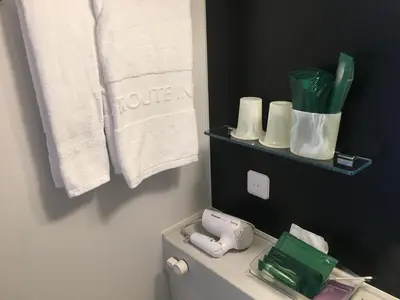 a bathroom with a toilet with a phone and towels at Hotel Route-Inn Grand Tokyo Toyocho in Tokyo