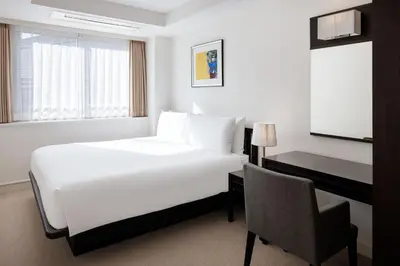 a hotel room with a bed and a desk and a chair at Oakwood Residence Aoyama Tokyo in Tokyo