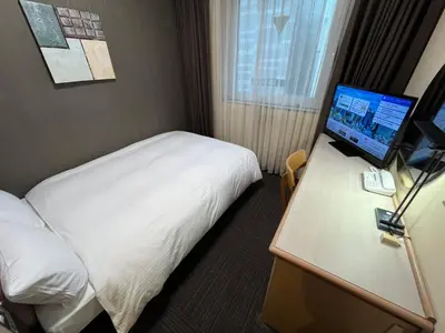 a hotel room with a bed and a computer on a desk at Hotel Route-Inn Tokyo Ikebukuro in Tokyo