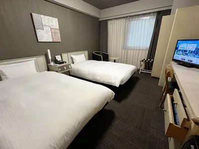 a hotel room with two beds and a flat screen tv at Hotel Route-Inn Tokyo Ikebukuro in Tokyo