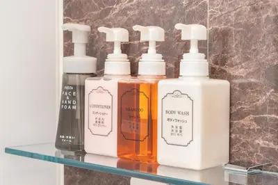 four bottles of soap on a glass shelf at Hotel Sunlite Shinjuku in Tokyo