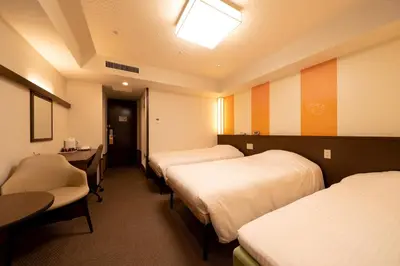 a hotel room with three beds and a desk and a table at Hotel Sunlite Shinjuku in Tokyo