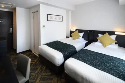 a hotel room with two beds and a chair at HOTEL MYSTAYS Hamamatsucho in Tokyo