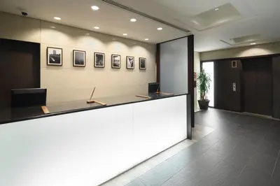 an office lobby with a reception counter with avertisement for at HOTEL MYSTAYS Hamamatsucho in Tokyo