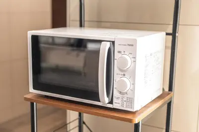 a microwave oven sitting on a wooden stand at HOTEL MYSTAYS Hamamatsucho in Tokyo
