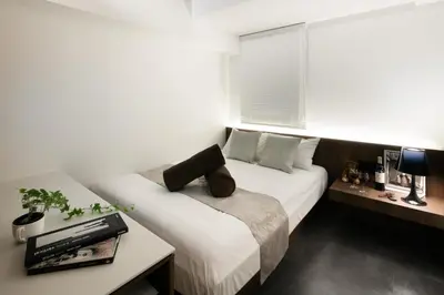 a bedroom with a bed and a table and a window at Hills Hotel Gotanda in Tokyo