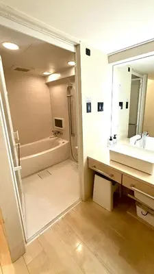 a bathroom with a tub and a sink and a mirror at Hills Hotel Gotanda in Tokyo