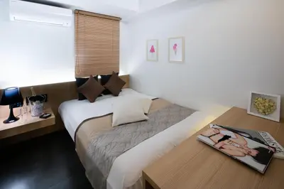 a bedroom with a bed and a table with a magazine at Hills Hotel Gotanda in Tokyo