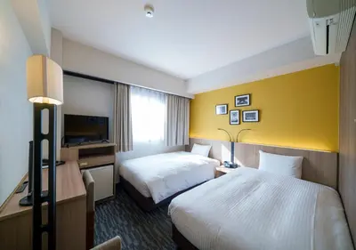 a hotel room with two beds and a television at Smile Hotel Tokyo Asagaya in Tokyo