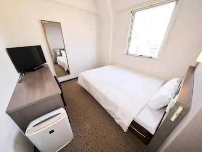 a small bedroom with a bed and a television at Super Hotel Tokyo Nihombashi Mitsukoshimae in Tokyo