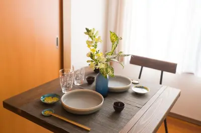 a wooden table with bowls and a vase with flowers at K&K Apartment Kita-Akabane #301 in Tokyo