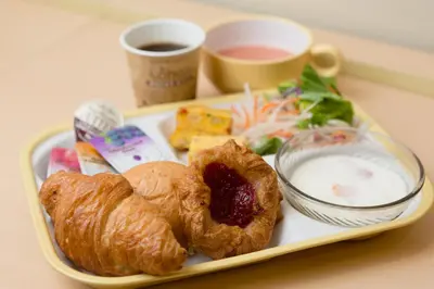 a tray with pastries and a cup of coffee and a plate of food at Super Hotel Tokyo Otsuka in Tokyo