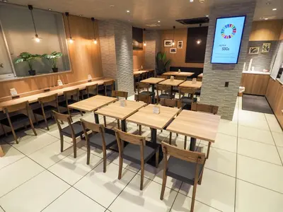 a restaurant with wooden tables and chairs and a screen at Super Hotel Tokyo Otsuka in Tokyo