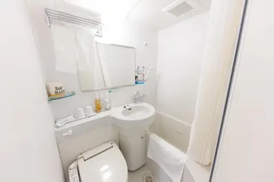 a bathroom with a toilet and a sink and a mirror at Super Hotel Tokyo Otsuka in Tokyo