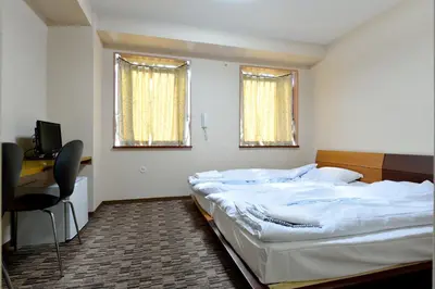 a bedroom with a bed and a desk and two windows at Juyoh Hotel in Tokyo