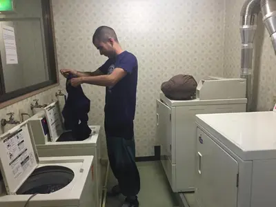 a man standing in a bathroom with a washing machine at Juyoh Hotel in Tokyo