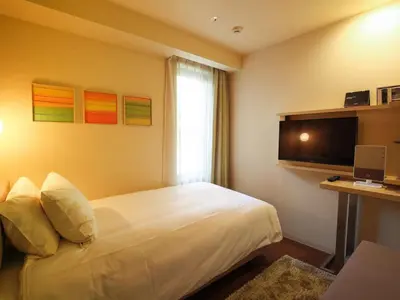 a hotel room with a bed and a television at Hotel Resol Ikebukuro in Tokyo