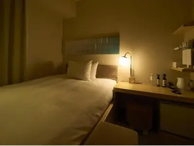 a bedroom with a bed and a desk with a lamp at Hotel Resol Ikebukuro in Tokyo