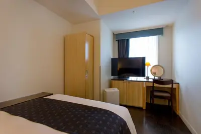 a hotel room with a bed and a flat screen tv at Hotel Monterey Ginza in Tokyo