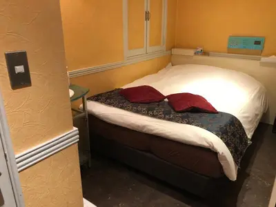 a small bedroom with a bed with two red pillows at Hotel U in Tokyo