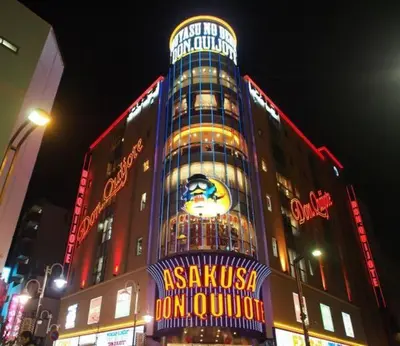 a tall building with neon signs on it at night at Mervielle Ueno in Tokyo