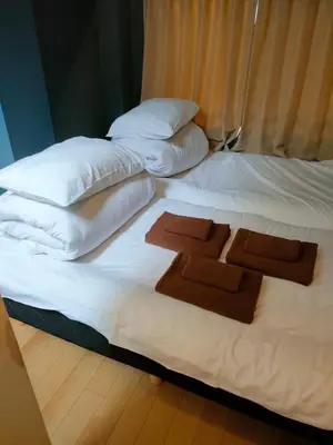 a large white bed with two brown towels on it at Mervielle Ueno in Tokyo