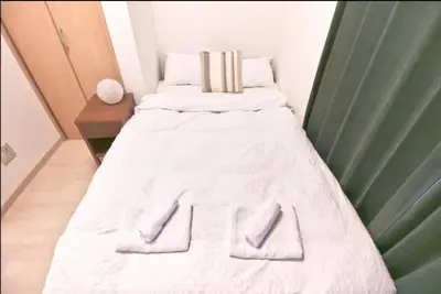 a bed with white sheets and two towels on it at Uhome Kanda Hotel in Tokyo