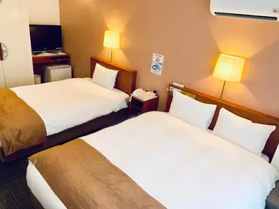 a hotel room with two beds and a phone at Tokyo Plaza Hotel in Tokyo