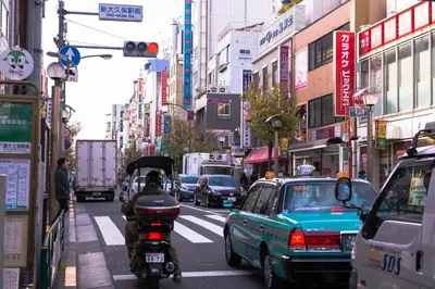 a busy city street with cars and a motor scooter at Tokyo Plaza Hotel in Tokyo