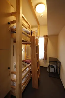 a room with bunk beds with a table and a desk at Hotel Palace Japan in Tokyo