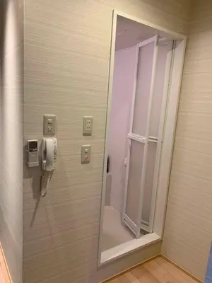 a bathroom with a mirror and a phone on a wall at Tabata Oji Hotel in Tokyo