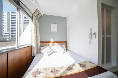 a bed in a room with a large window at Tabata Oji Hotel in Tokyo