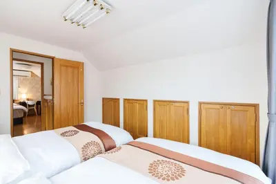 two beds in a bedroom with wooden cabinets at Luxury Guest House in Tokyo Shinjuku in Tokyo
