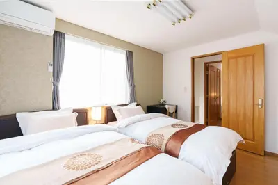 two beds in a room with a window at Luxury Guest House in Tokyo Shinjuku in Tokyo