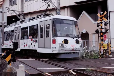 a white train with a cat painted on its at \u4e16\u7530\u8c37 kamikitazawa sta \u5927\u6676\u5bb6direct to Shinjuku for 13min \u4e0a\u5317\u6ca23\u5206 \u8fd1\u6d89\u8c37\u65b0\u5bbfjust 230m from sta in Tokyo