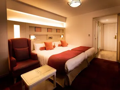 a hotel room with a large bed and a chair at Hotel Bellclassic Tokyo in Tokyo