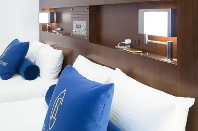 a bedroom with a bed with blue and white pillows at Hotel Bellclassic Tokyo in Tokyo