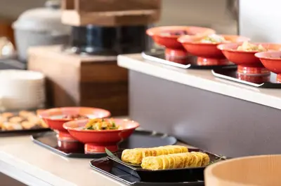 a buffet line with plates of food and bowls of food at Hotel Bellclassic Tokyo in Tokyo