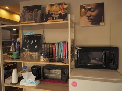 a kitchen with a microwave and a shelf with books at bnb+ Secret Base Mejiro in Tokyo