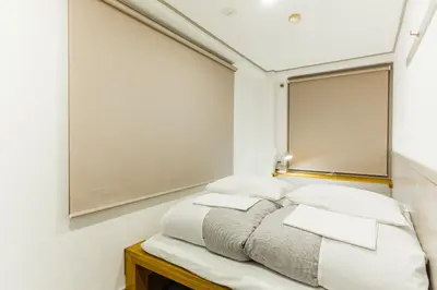 a bed in a room with a mirror on the wall at Shinagawa-shuku Guest House & Tours in Tokyo