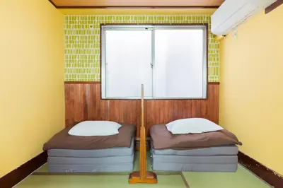 two beds in a room with a window at Shinagawa-shuku Guest House & Tours in Tokyo