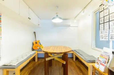 a room with a table and benches and a guitar at Shinagawa-shuku Guest House & Tours in Tokyo