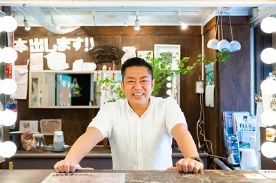 a man standing at a table in a store at Shinagawa-shuku Guest House & Tours in Tokyo